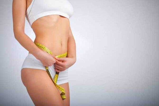 The slender girl measures the volume of waist